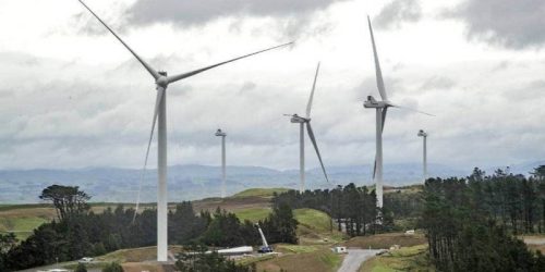 Operational wind turbines towering over a rural landscape with cloudy skies, emphasising sustainable energy production and environmental conservation